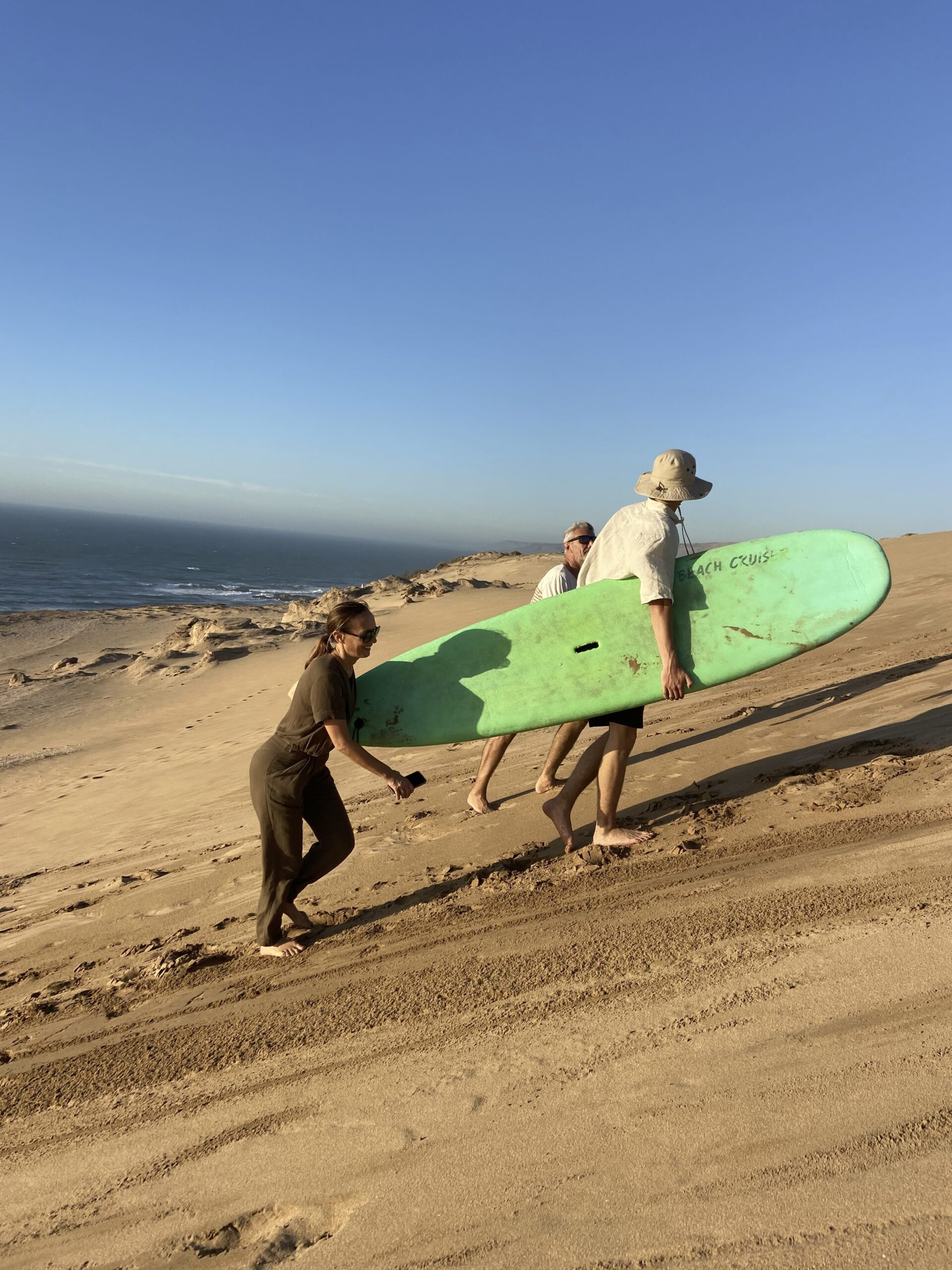 Traveler sliding down Timlalin dunes sandboarding Morocco