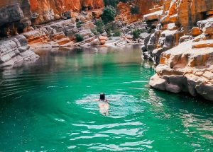 Tourists swimming and relaxing in the emerald pools of Paradise Valley during a day trip from Taghazout